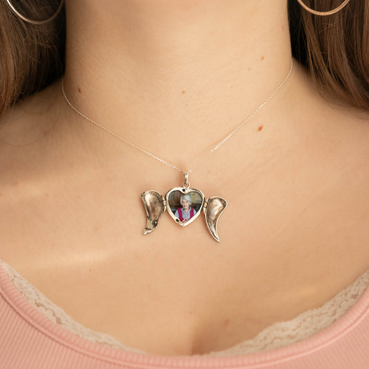 Model wearing silver heart locket with anel wings