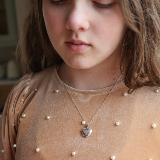 Model wearing tan top with heart shaped locket