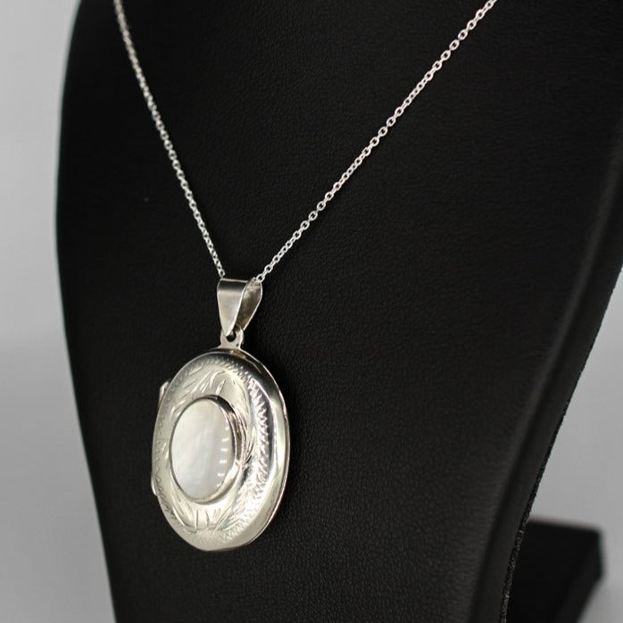 Oval shaped embellished silver photo locket necklace with white mother of pearl inlay on Italian silver chain displayed on black bust.