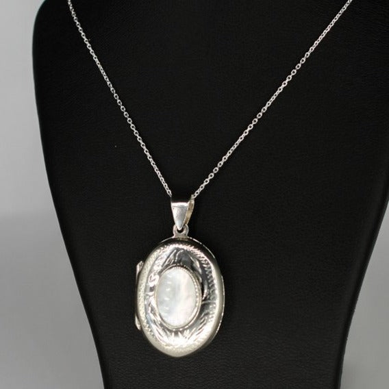 Oval shaped embellished silver photo locket necklace with white mother of pearl inlay on Italian silver chain displayed on black bust.