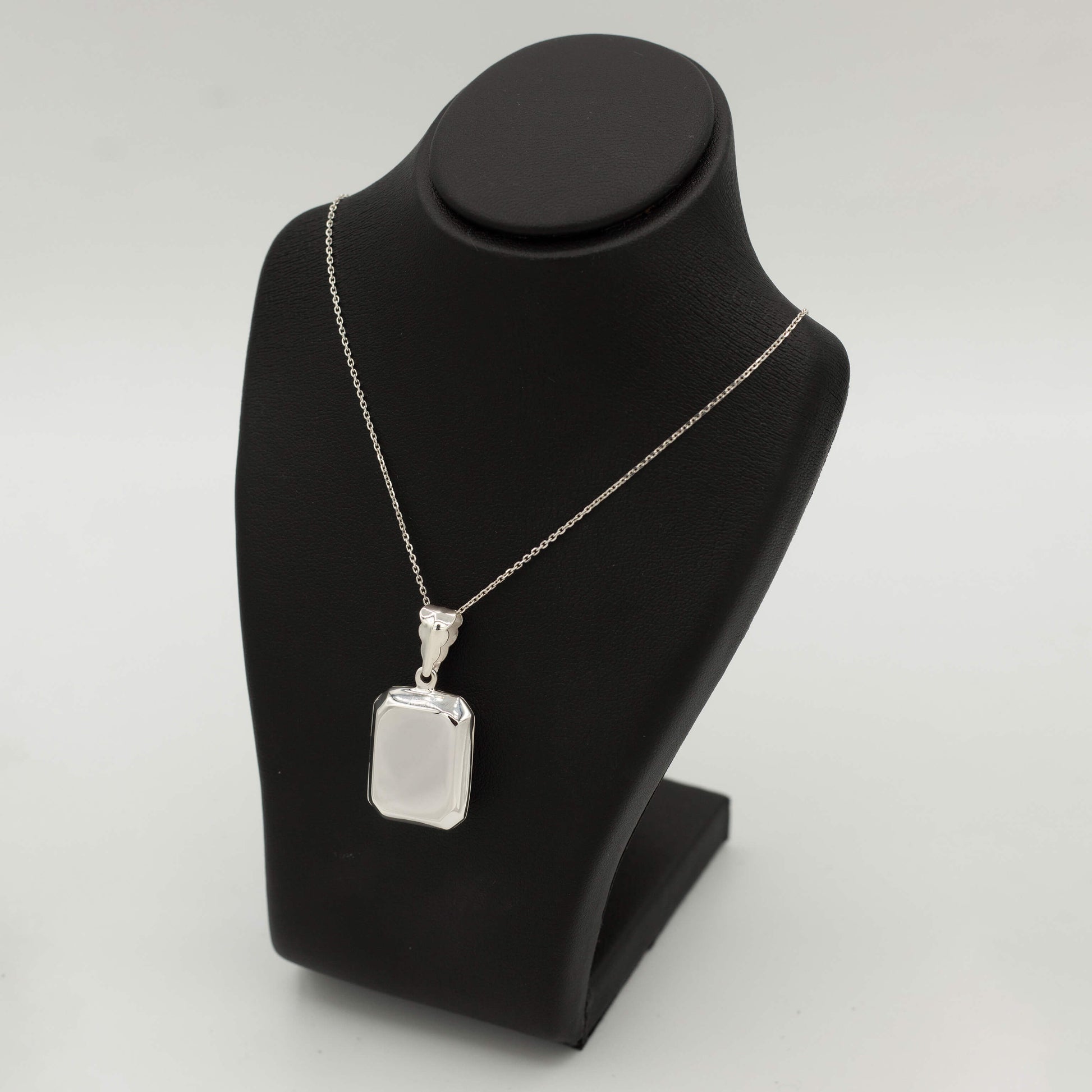 Silver rectangle shaped locket hung on a black bust