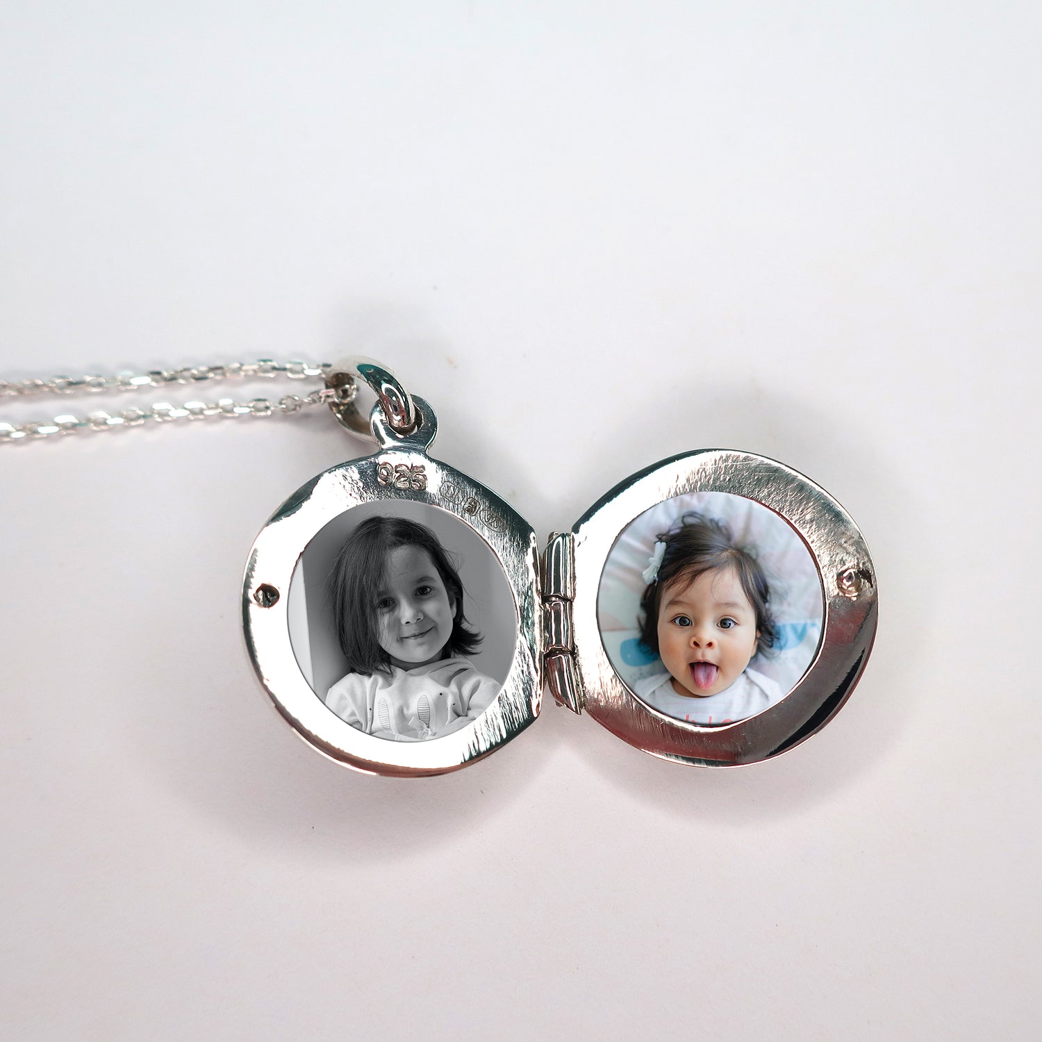 round photo locket open revealing two photos of children against a pink background