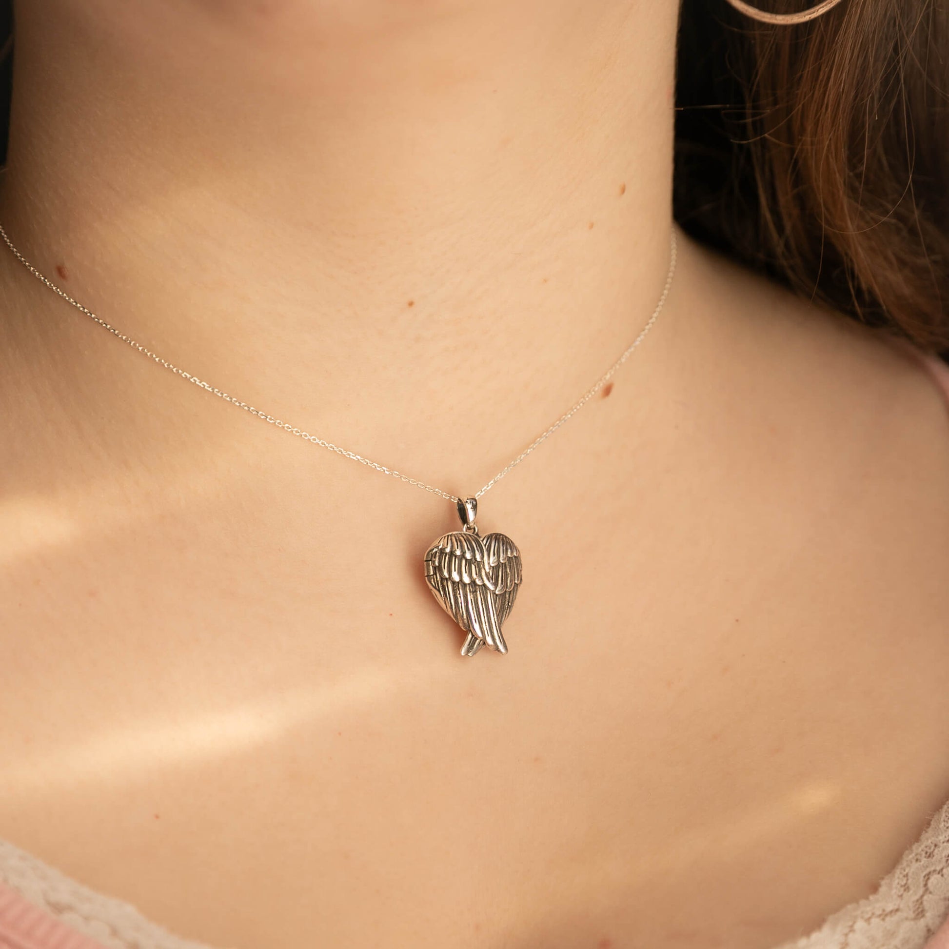 Silver angel wing necklace on a person's neck