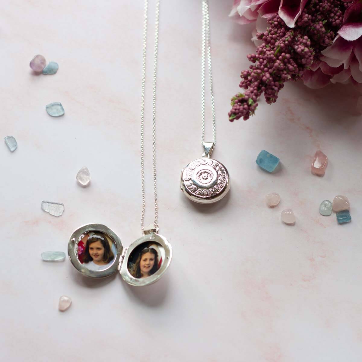 large silver locket open showing two photos.