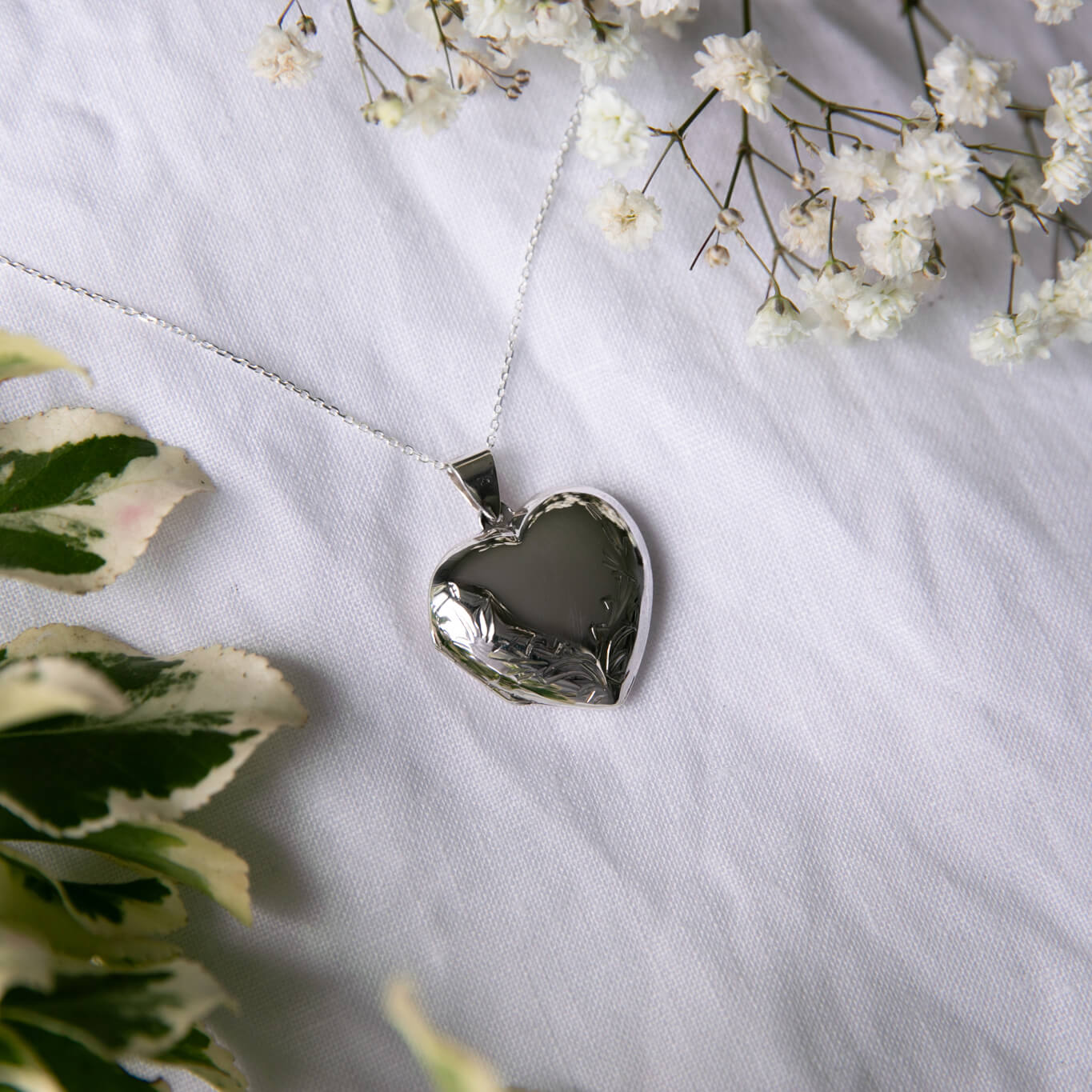 Large heart shaped locket necklace on a white linen background