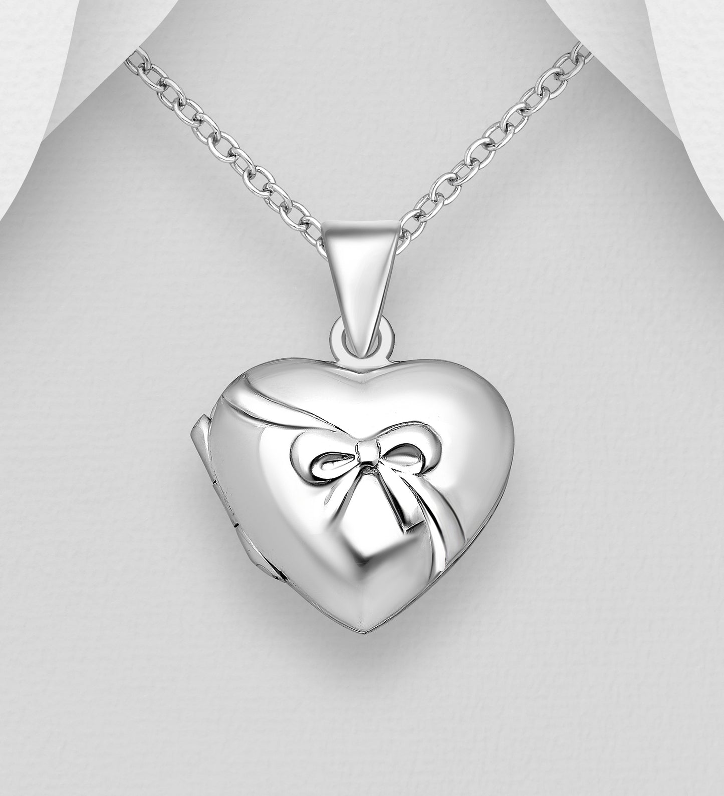 Silver heart shaped locket with bow embellishment. 