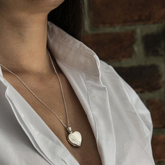 Model wearing white shirt and silver heart-shaped locket pendant with silver chain