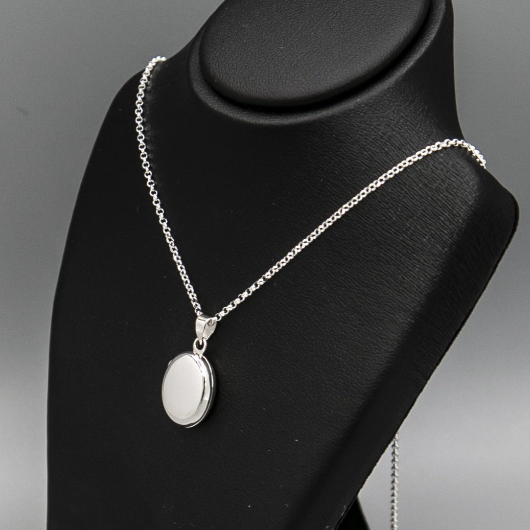 Small silver locket necklace displayed on black bust
