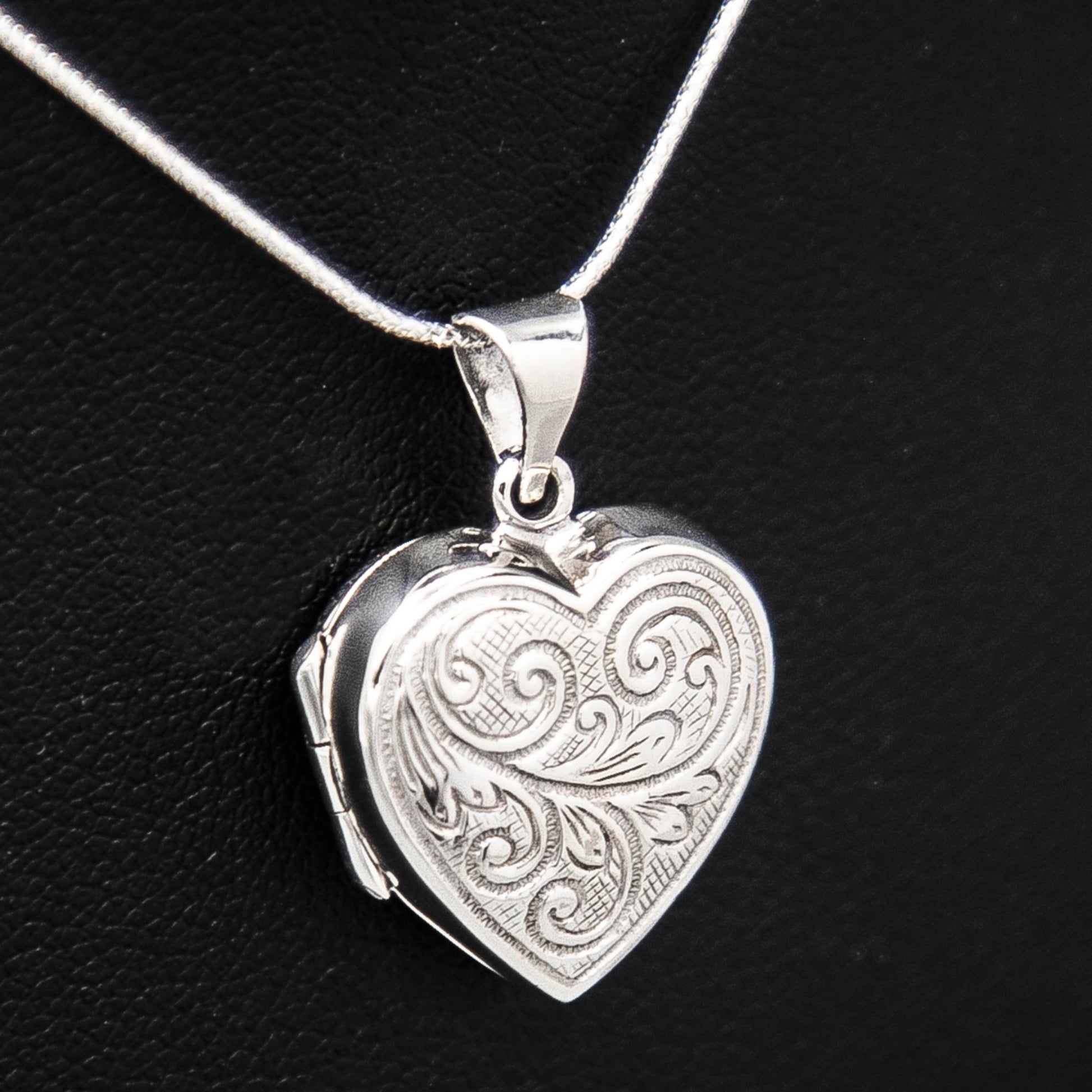 Silver Necklace locket pendant with embellishment on silver chain displayed on black