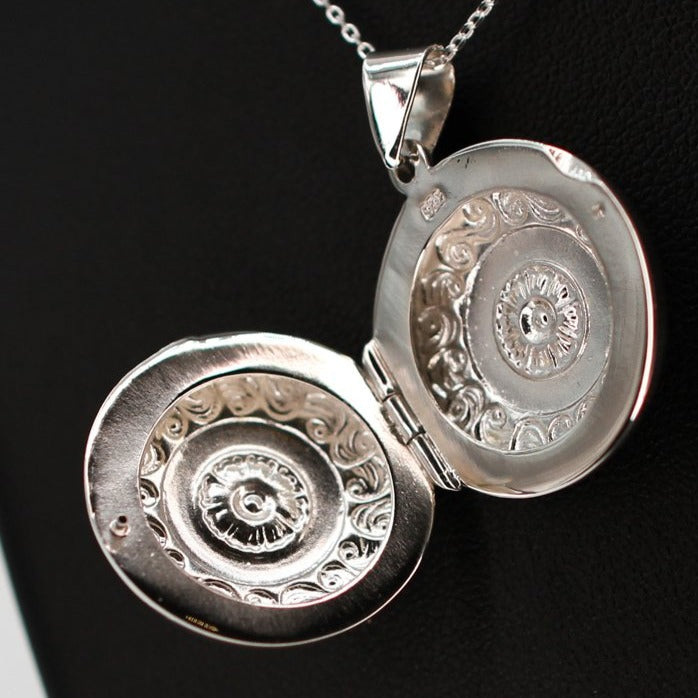 Large silver locket on a silver chain. The locket is open.