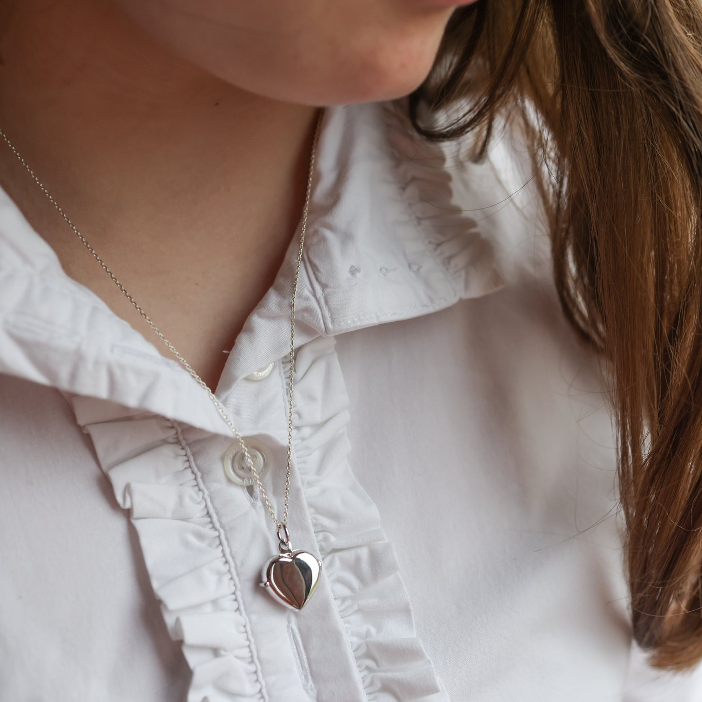 model wearing white shirt and silver heart shaped photo necklace