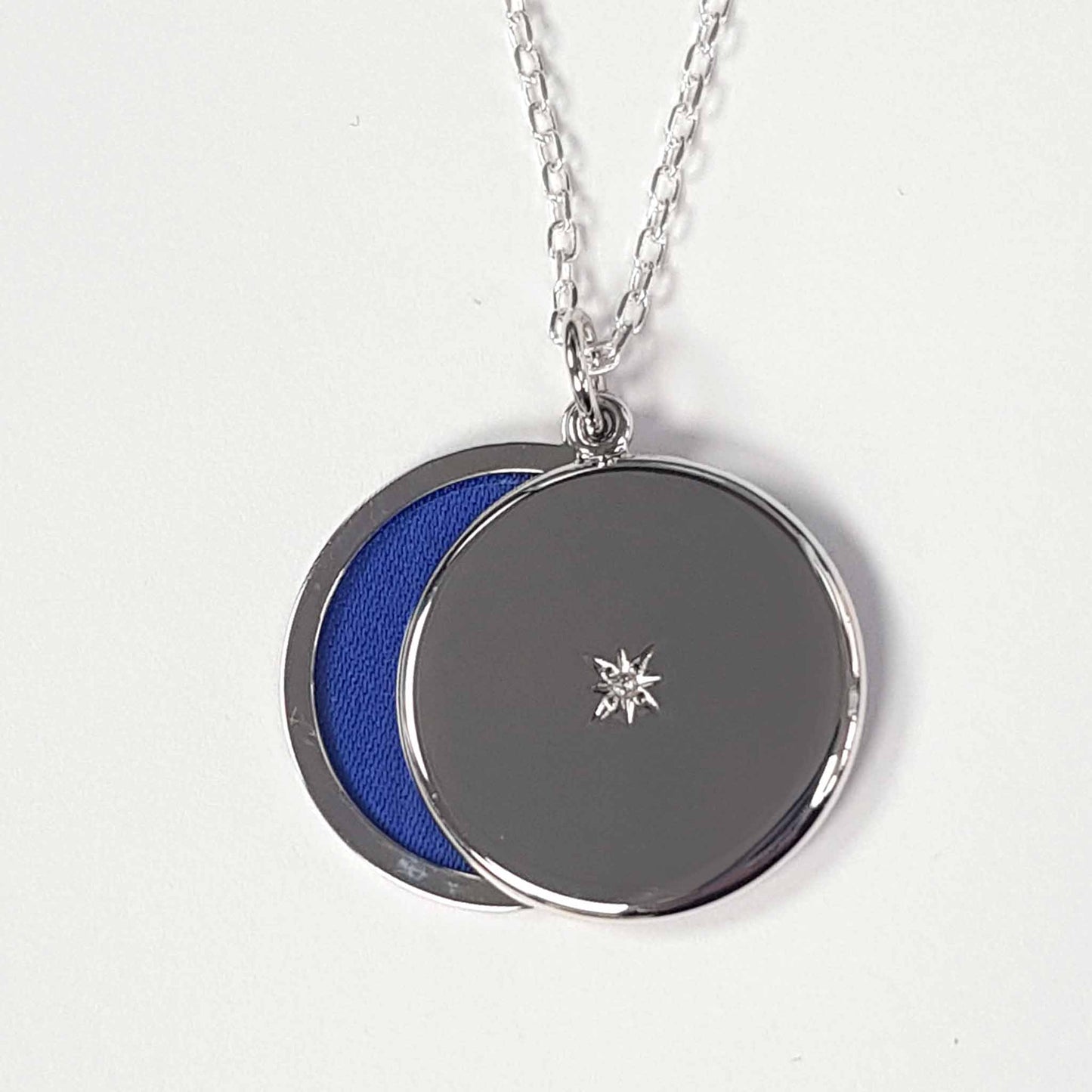 Round sterling silver locket with chain open to reveal blue insert