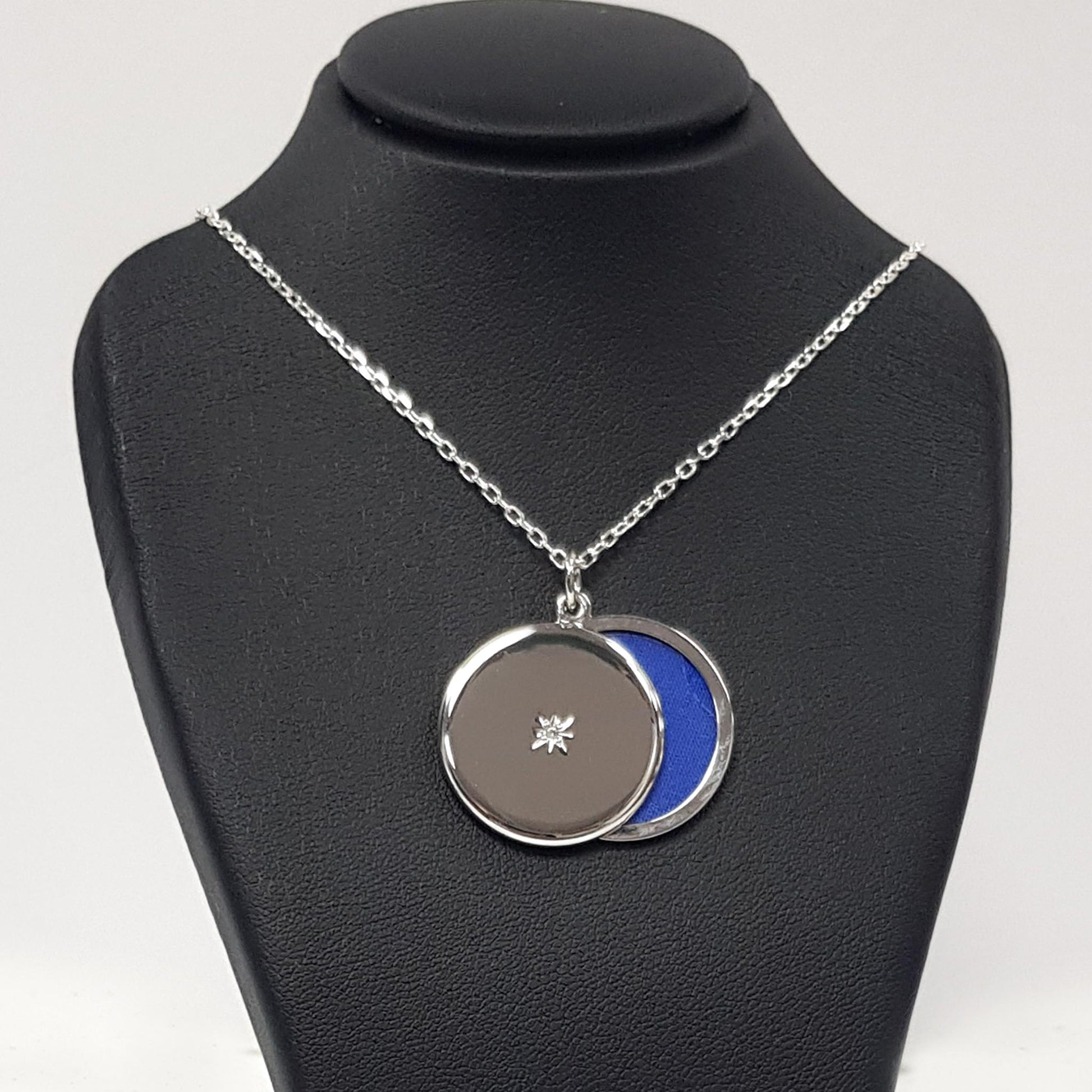 Round silver locket with cubic zirconia star in the centre photographed on a black bust