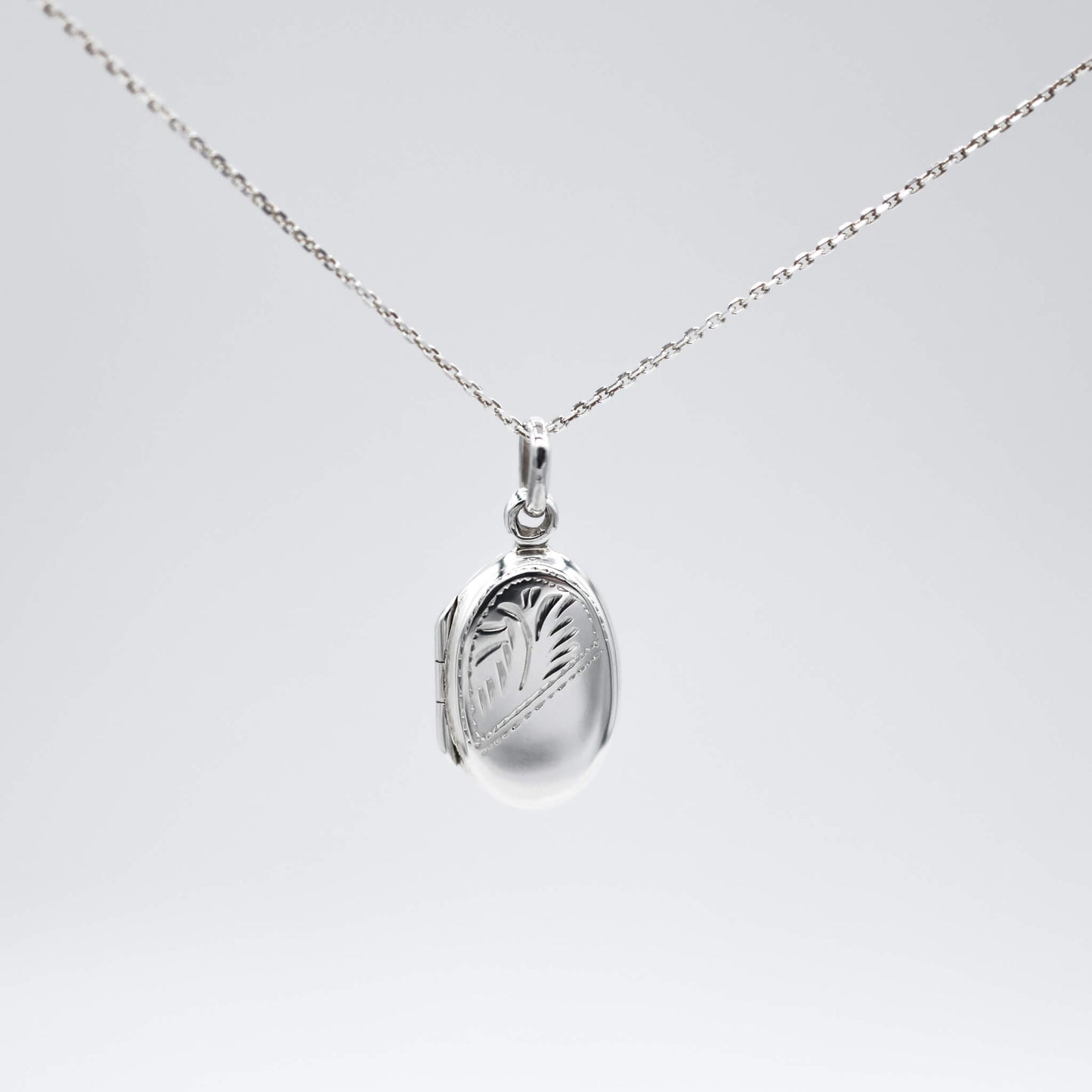 Oval silver locket with photos and silver chain on a white background