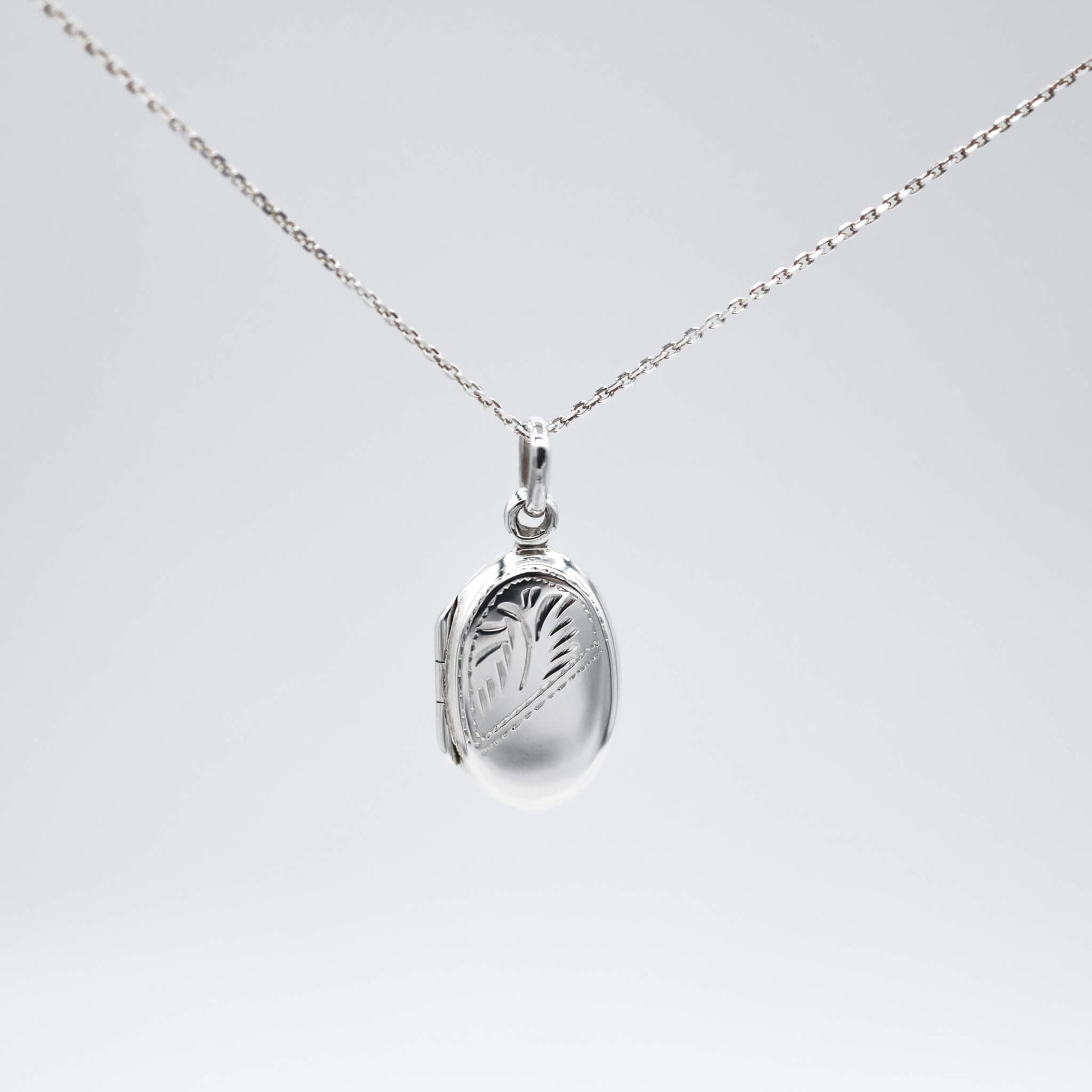 Oval silver locket with photos and silver chain on a white background